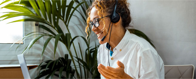 woman with headset speaking to someone on laptop